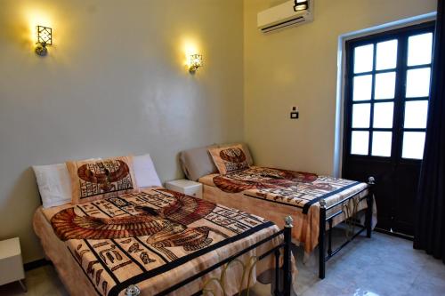 two beds in a room with a window at Luxor Sapphire in Luxor
