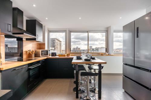 une cuisine avec des armoires noires et une petite table. dans l'établissement Le Prouvé II - Très bel appartement climatisé, à Nancy