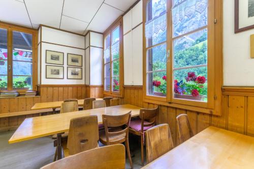 a dining room with tables and chairs and windows at Alpenhof Mountain Lodge in Stechelberg