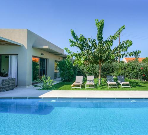 a swimming pool with chairs and a house at Olimpia Villas I Luxury villas with private pools! in Epáno Kefalás
