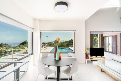 a living room with a table and chairs and a pool at Olimpia Villas I Luxury villas with private pools! in Epáno Kefalás