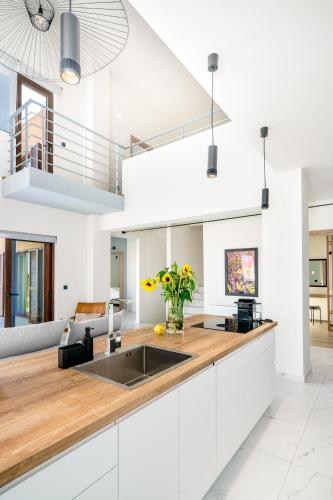 a kitchen with white cabinets and a wooden counter top at Olimpia Villas I Luxury villas with private pools! in Epáno Kefalás