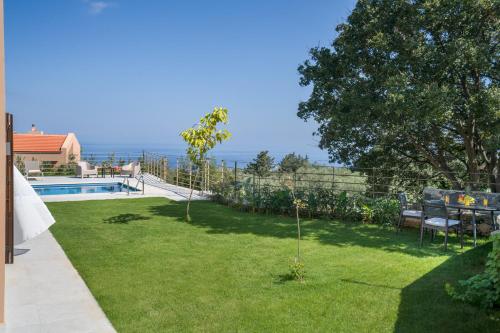 a garden with a view of the ocean at Olimpia Villas I Luxury villas with private pools! in Epáno Kefalás