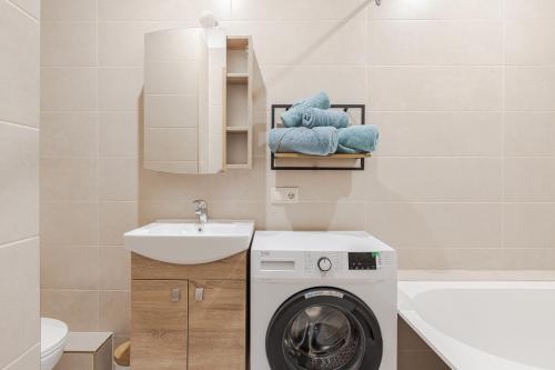 a bathroom with a washing machine and a sink at Marmor House in Rīga