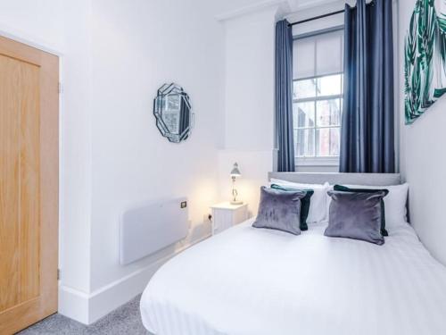 a bedroom with a white bed with blue curtains and a window at Modern 2-Bed Apartment in City Centre in Hull