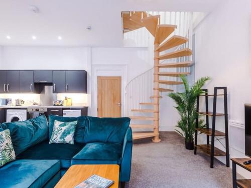 a living room with a blue couch and a spiral staircase at Modern 2-Bed Apartment in City Centre in Hull
