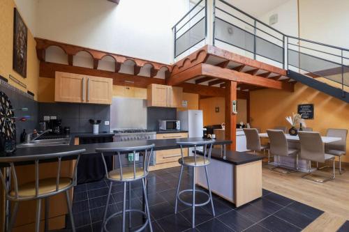 une cuisine avec tabourets de bar et escalier dans l'établissement La Pépite, à Ambérieu-en-Bugey