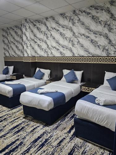 a room with three beds with blue pillows at فندق سواعد العالمية مكة المكرمة الحرم - Sawaed International Hotel Makkah Al-Haram in Mecca