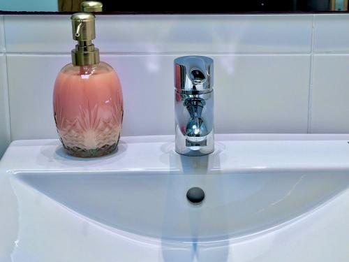 lavabo con dispensador de jabón y botella de cristal en Apartamentos Arcos Costa Cálida, en Águilas
