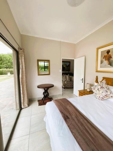 a bedroom with a large bed and a table at 3B Annie's Place Rawdons Country Estate in Nottingham Road