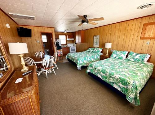 a bedroom with two beds and a table with a fan at Sand Spur Cottages in Nags Head