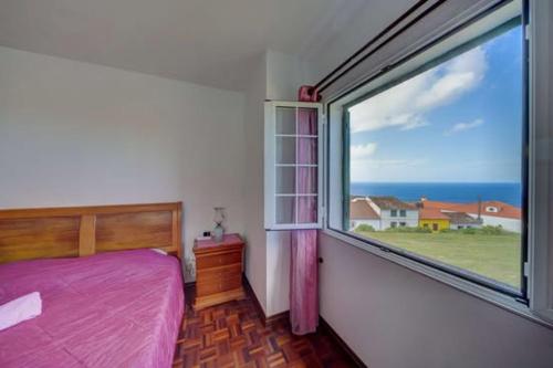 a bedroom with a bed and a large window at Pérola Achadense Guesthouse in Achada