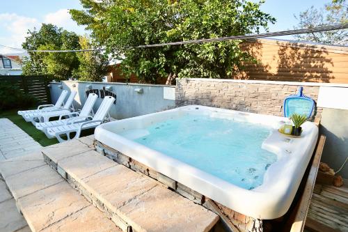 a hot tub on a patio with two chairs at אצולת הכנרת in Kallanit