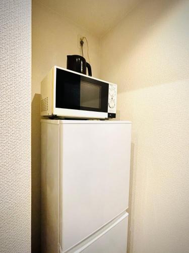 a microwave sitting on top of a refrigerator at 嵐 Arashi BNB 日本橋 No8111 in Osaka