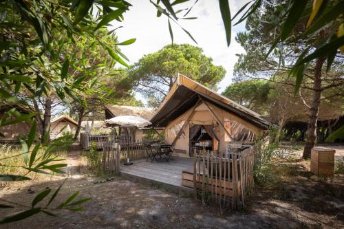 a luxury tent with a deck in a forest at Huttopia Lagoa de Óbidos in Casal do Narcizo