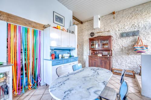 une cuisine avec une table et des chaises dans une pièce dans l'établissement maison de famille, à Mortagne-sur-Gironde