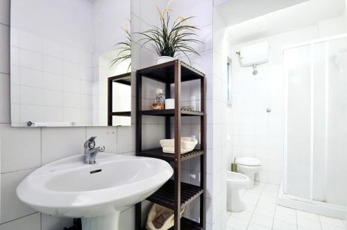 a white bathroom with a sink and a toilet at Uffizi Apartment in Florence