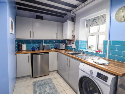 a kitchen with white cabinets and a washer at Golygfa'r Orsaf Snowdonia National Park in Bala