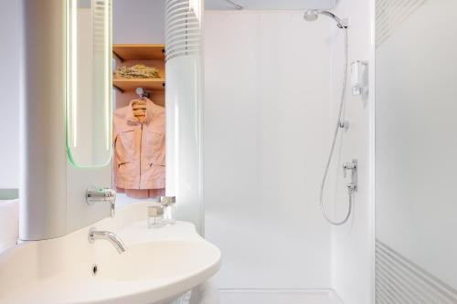 a white bathroom with a sink and a shower at Ibis Budget Bamberg in Bamberg