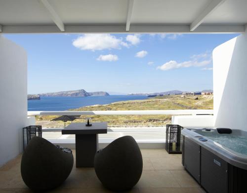 a room with a large window with a table and chairs at Absolute Paradise Santorini in Akrotiri