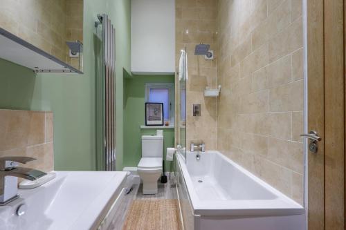 a bathroom with a tub and a toilet and a sink at Leah Suite by Koya Homes - 2 Bed, 2 Bath, Pool Table, Sea View, Free Parking in Barry