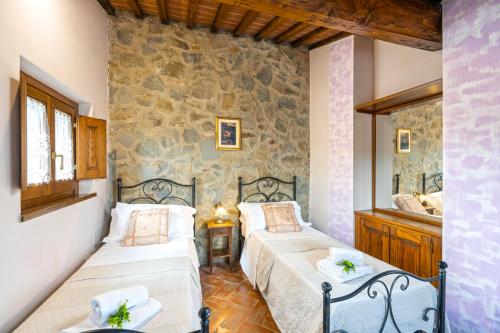 1 Schlafzimmer mit 2 Betten und einer Steinmauer in der Unterkunft Dimora di Castroncello in Castiglion Fiorentino