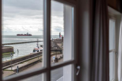 a window with a view of the ocean and a ship at Boutique Hotel Maldegem in Vlissingen