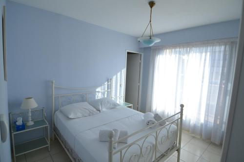 une chambre avec un lit blanc et une fenêtre dans l'établissement HELIANTHE - Superbe appartement avec terrasse vue mer et Château au Port de Nice, à Nice