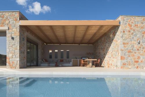 a house with a swimming pool next to a stone wall at VK Villas - Votsalo & Kyma Villas, By ThinkVilla in Léntas