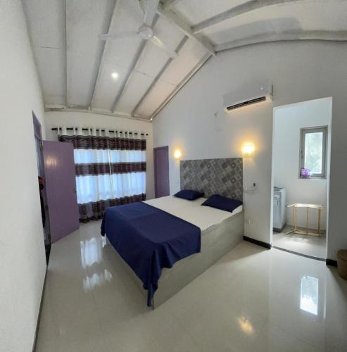 a bedroom with a large bed with a blue blanket at House 73 in Unawatuna