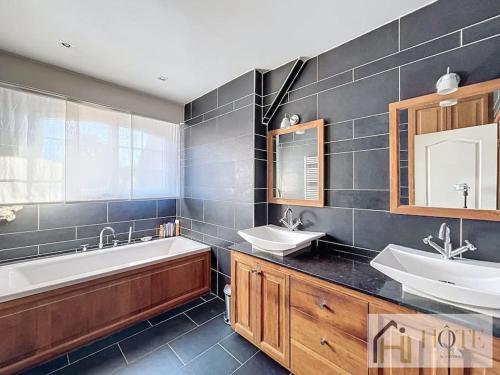 un ampio bagno con due lavandini, una vasca e un motto tubermottere di Le Domaine Sérénité - Maison de caractère a Dunkerque