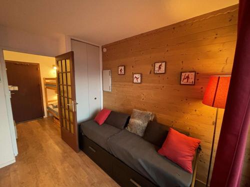 - un salon avec un canapé et un mur en bois dans l'établissement Studio cabine au pied des pistes, 3 couchages, parking - FR-1-297-326, à Auris