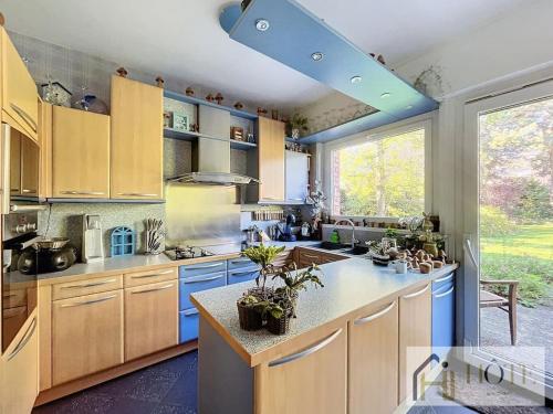 une grande cuisine avec des placards bleus et une grande fenêtre dans l'établissement Le Domaine Sérénité - Maison de caractère, à Dunkerque