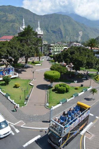 a double decker bus driving down a city street at Hotel Elvita Spa in Baños