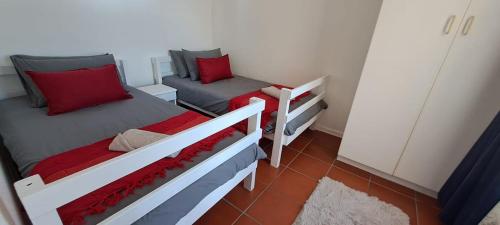 2 camas en una habitación pequeña con almohadas rojas en Unit 75 Hermanus Beach Club, en Hermanus