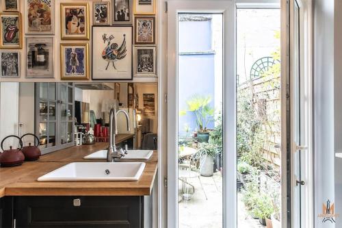 une salle de bain avec un lavabo, un miroir et une fenêtre dans l'établissement Montmartre with private courtyard, à Paris