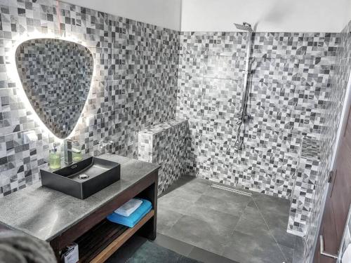 Un baño con lavabo y ducha con espejo. en Villa Masay Antananarivo, en Antananarivo