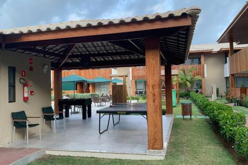 a wooden pergola with a table in a courtyard at Paraíso da Lagoa, Praia de Itacimirim Village novo! in Itacimirim
