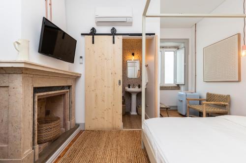 a bedroom with a bed and a tv and a fireplace at Amália Boutique Suites & Studios - by @ rita´s place in Faro