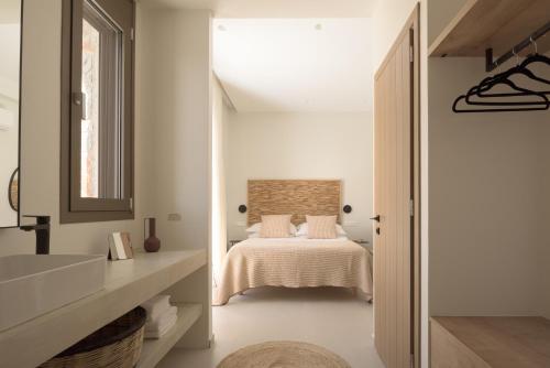 a white bedroom with a bed and a mirror at VK Villas - Votsalo & Kyma Villas, By ThinkVilla in Léntas
