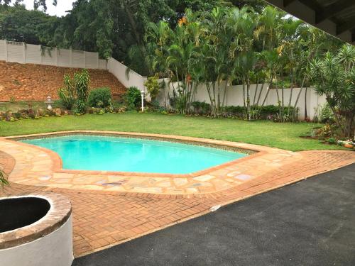 a swimming pool in a yard with a brick driveway at The Grand Orchid Guesthouse in Durban