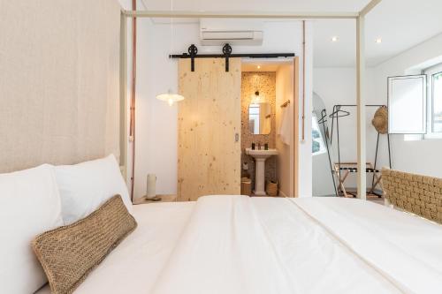 a bedroom with a white bed and a bathroom at Amália Boutique Suites & Studios - by @ rita´s place in Faro