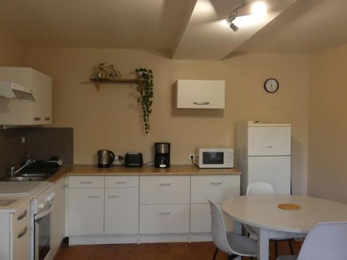 une cuisine avec une table et un réfrigérateur blanc dans l'établissement L'instant détente, à Saint-Léger-de-Montbrillais