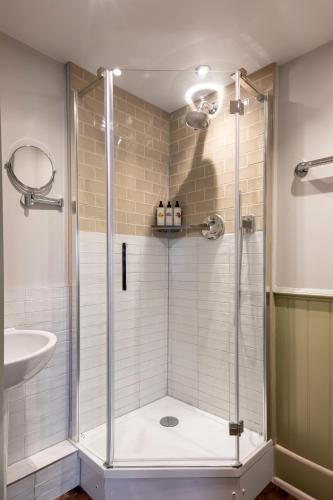 a shower with a glass door in a bathroom at Coach & Horses Hotel in London