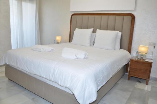 una camera da letto con un letto grande con lenzuola e cuscini bianchi di Miramar Prestigia a Ville Nouvelle