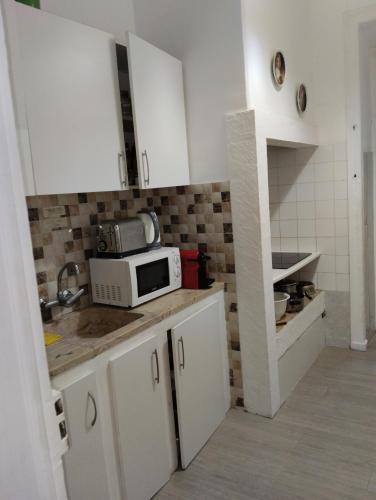 a kitchen with white cabinets and a microwave on a counter at Quarto C in Lisbon