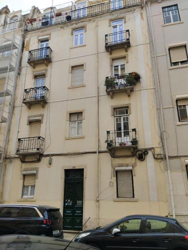 a tall building with balconies and a car parked in front at Quarto C in Lisbon