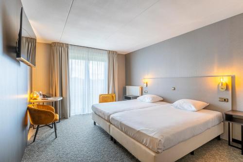 a hotel room with a large bed and a television at Parkhotel Horst - Venlo in Horst