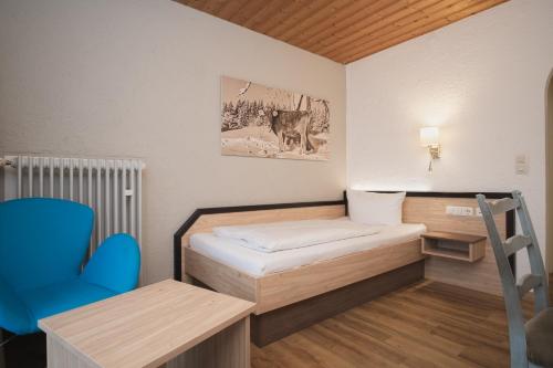 a small room with a bed and a blue chair at Trail Hotel Oberstaufen in Oberstaufen