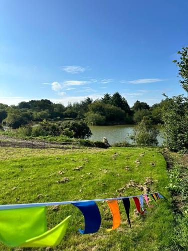 a row of prayer flags in a field with a lake at Lakeside Glamping Kingfisher in Saint Columb Major